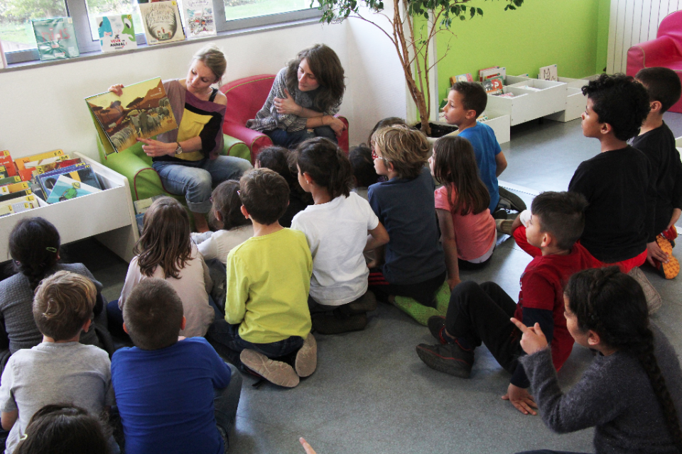 Une bibliothécaire présente l'auteure Anne-Sophie Baumann à des enfants de l'école élémentaire Jean-Moulin