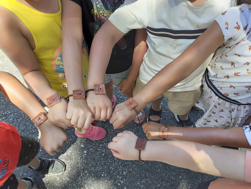 Les enfants présentent les bracelets qu'ils ont réalisés dans le cadre des activités faites avec Evade.