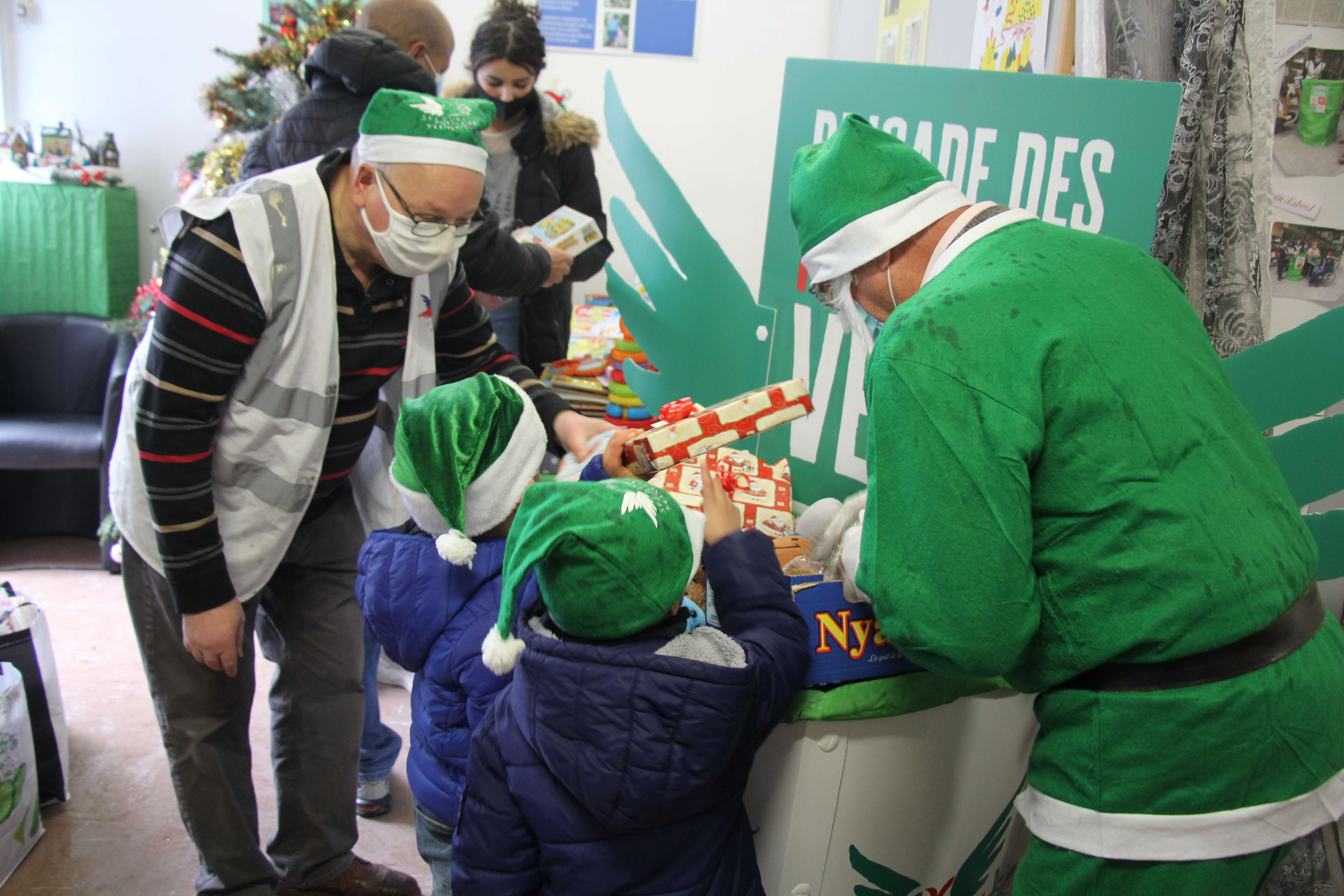 Le Père Noël vert et les lutins de sa brigade distribuent des jouets neufs aux enfants.