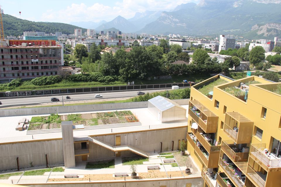 Photo prise depuis un appartement en hauteur du bâtiment Golden parc. Vue plongeante sur l'ilot central paysagé, les jardins partagés et les toitures végétalisées.