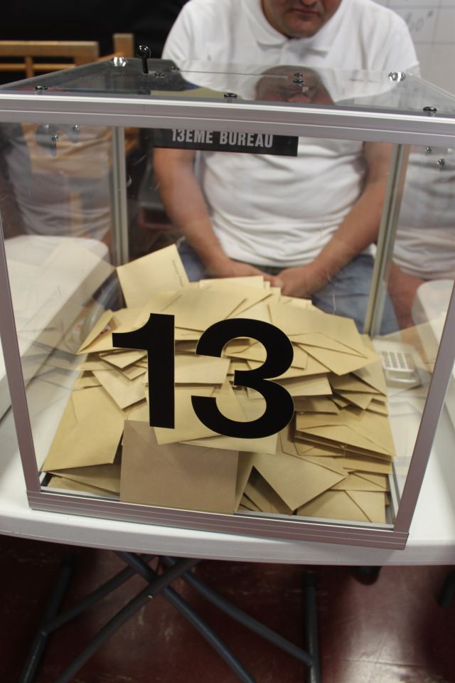 Photo d'une urne avec le numéro 13, remplis de bulletins de vote lors d'une élection.