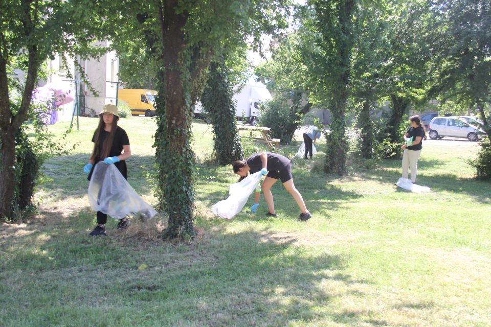Photo prise dans le cadre de l'opération Ville propre. Nous voyons un groupe de jeunes filles, encadré par les éducateurs des services des sports et prévention de la Ville, avec des gants, des sacs, ramassant les déchets par terre.