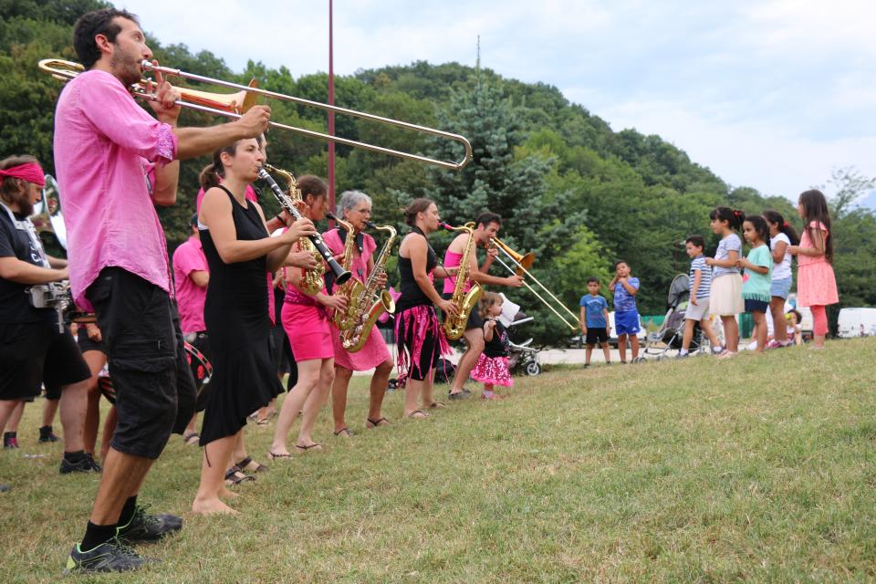 Habillés de rose et de noir, les musicien-nes de la fanfare Pink it black jouent au milieu du parc, entouré-es de leur public.