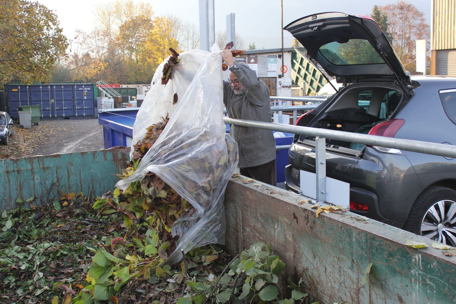 Personne jetant des feuilles mortes à la déchèterie