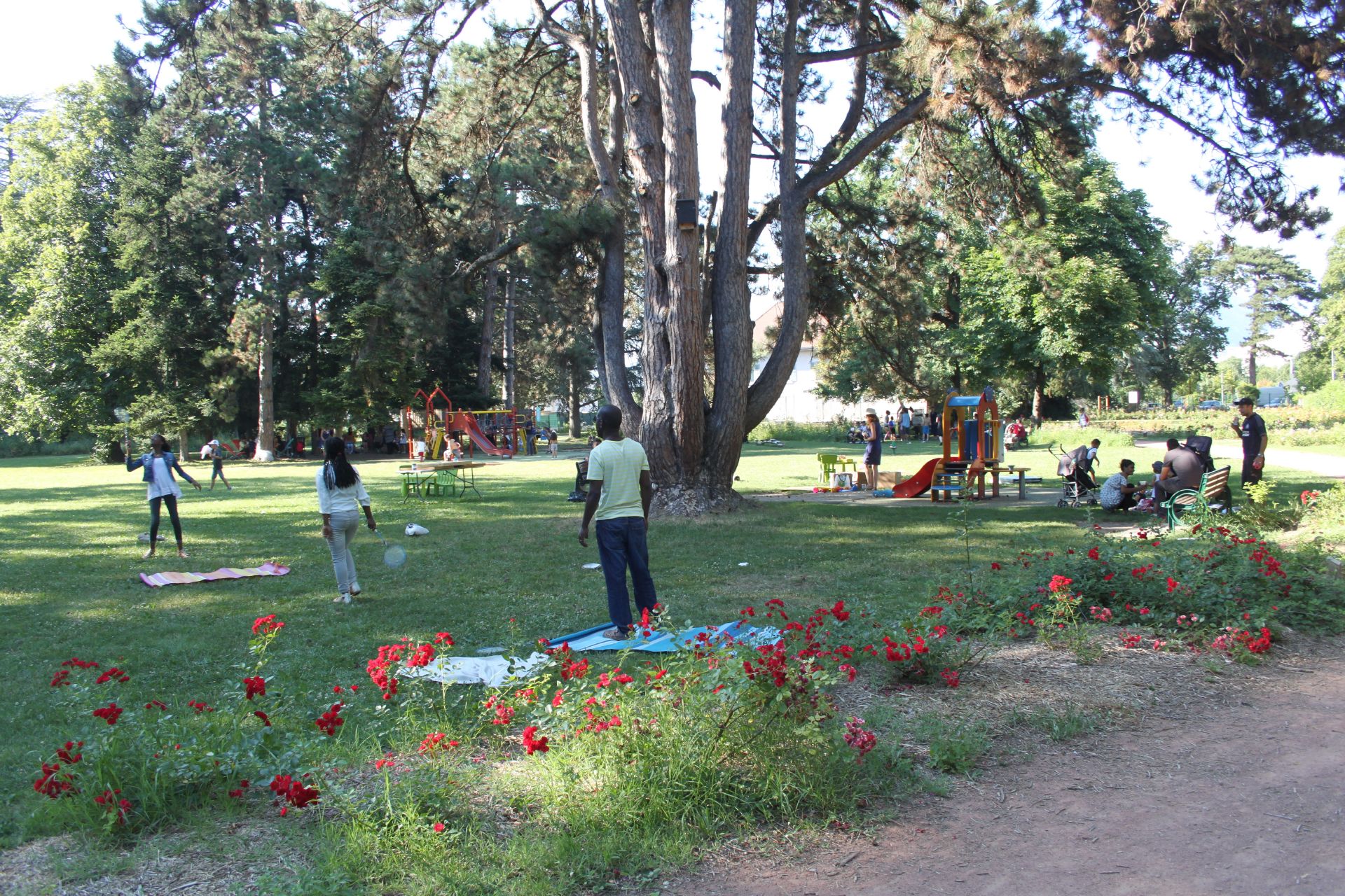 Des enfants et adultes s'amusent sur et autour des jeux du parc géo-Charles