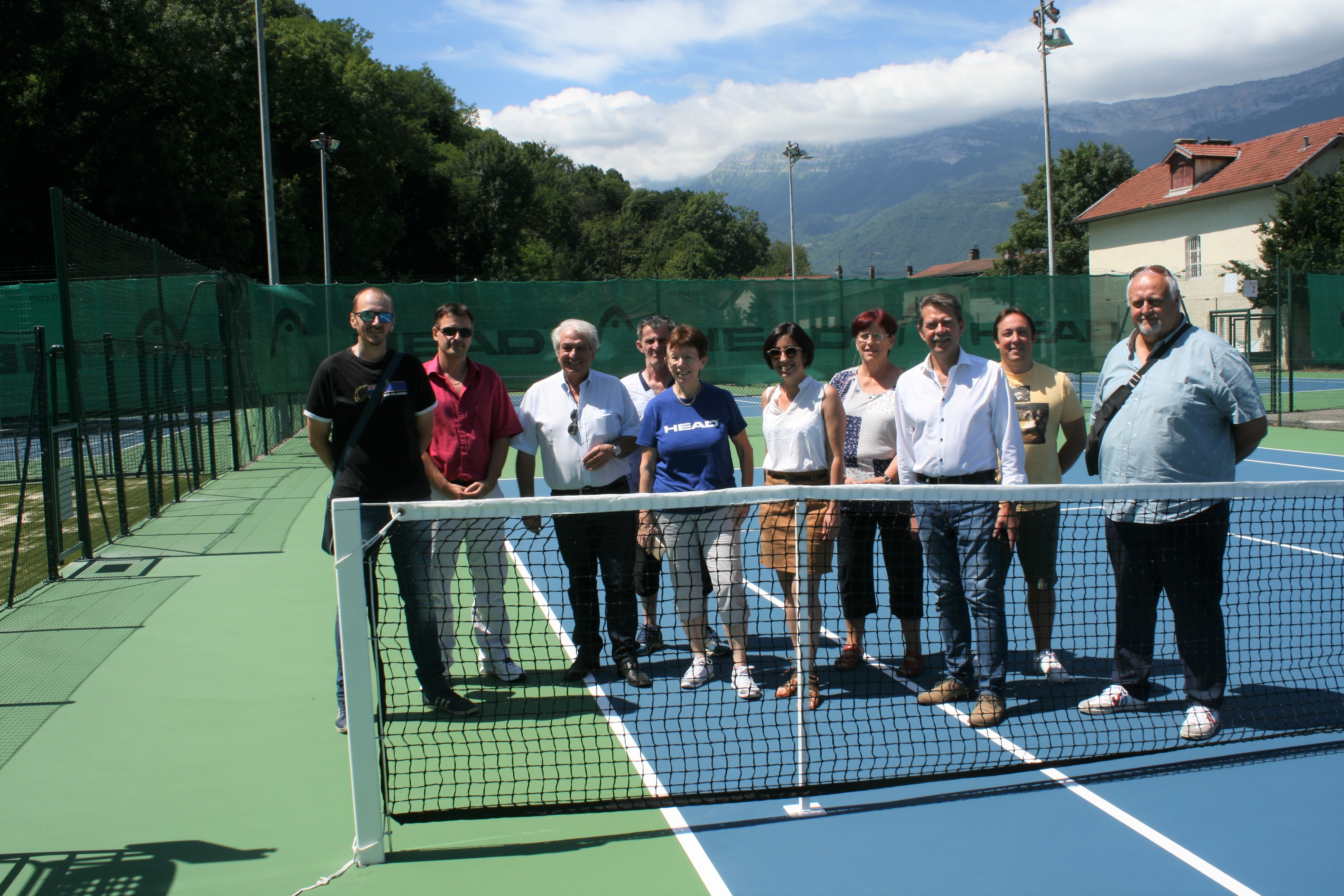 Les membres du Tennis club Echirolles, dont le président Arnaud Voisin, Michel Amat, vice-président du comité de l'Isère et les élu-es, dont le maire Renzo Sulli, Amadine Demore, 1ère adjointe, Daniel Bessiron, 2e adjoint, et Cédric Brest, conseiller municipal délégué à la relation avec les clubs sportifs, posent devant les filet sur les courts rénovés. 