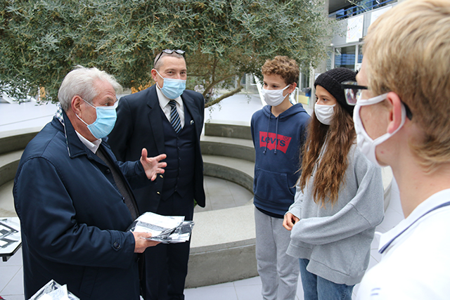 Le maire distribue des masques à quelques lycéen-nes en présence du proviseur du lycée.