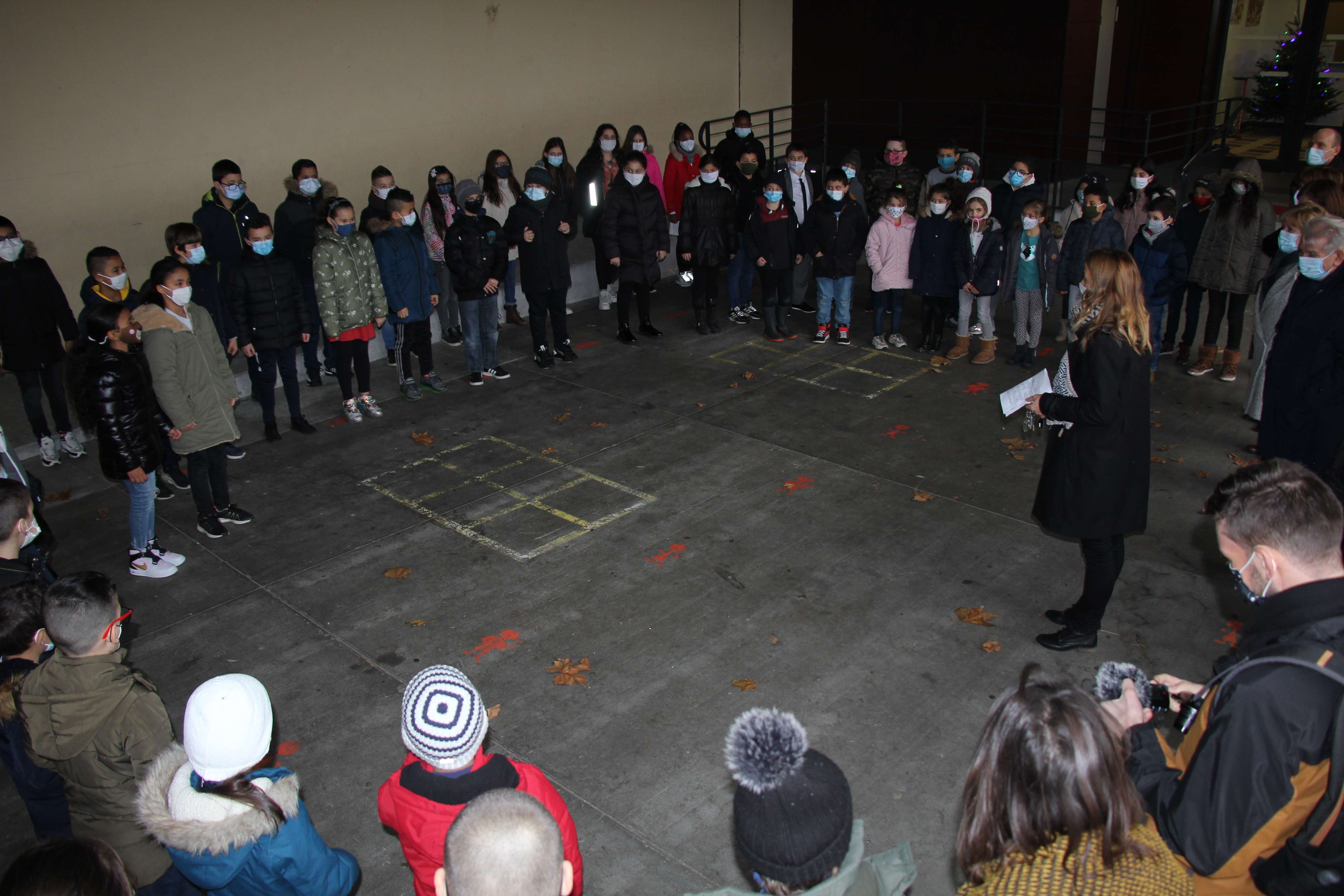 Au terme de la visite, malgré le froid, les élèves ont interprété Liberté, de Paul-Eluard, sous le préau de l'école. Les enfants se tiennent en arc de cercle face à leur professeur. En face d'eux le public les écoute.
