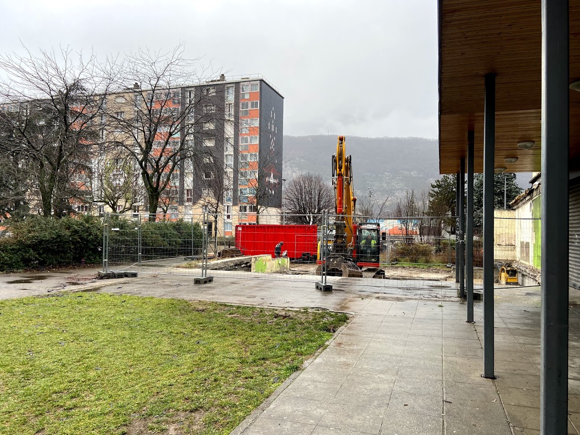 Vue sur un espace en travaux. Un local a été démoli et nous voyons l''espace libéré entouré de barrières en attendant d'être entièrement végétalisé.