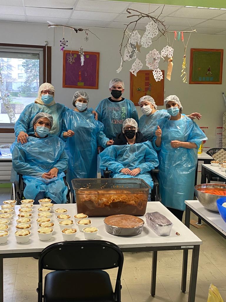 Repas solidaire organisé par le Secours populaire pour les étudiant-es L'équipe de bénévoles, tous masqués, pose dans les locaux prêtés par la SDH. Ils portent tous des charlottes et des blouses bleues de protection.