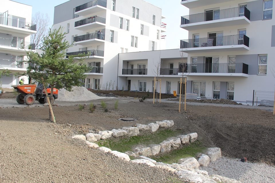 Vue sur le programme immobilier Open set. Un petit jardin est en cours d'aménagement au milieu de plusieurs immeubles.