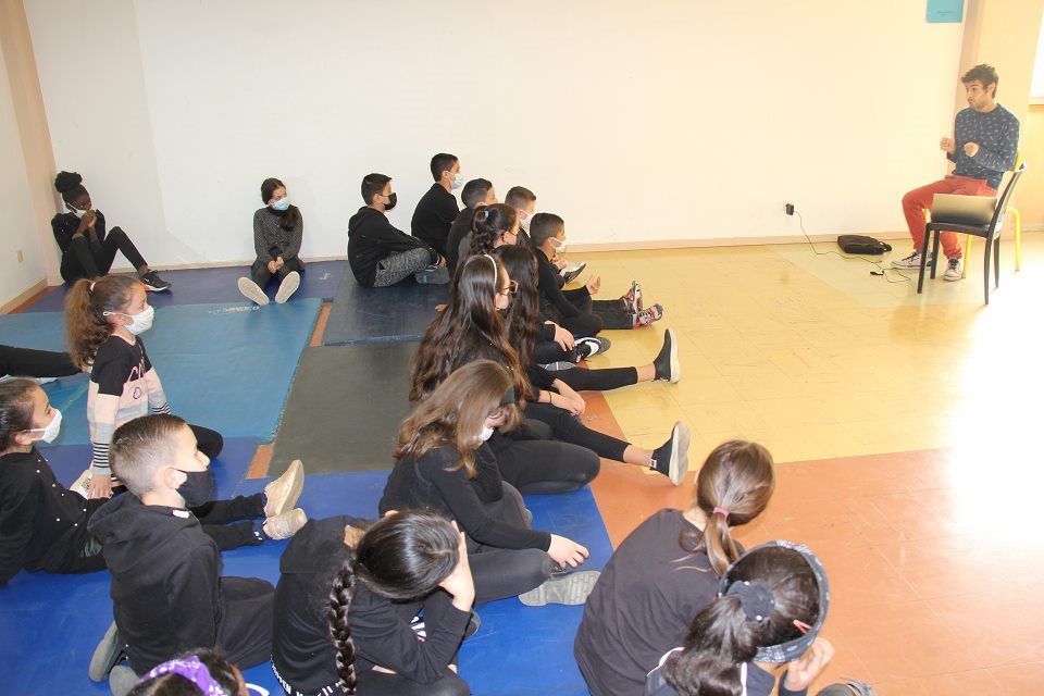 Projet THEA à l'école Jean-Moulin , Antonio Carmona lit aux enfants un large extrait du début de son prochain livre. Il est assis sur une chaise face aux enfants qui sont eux installés sur des tapis.