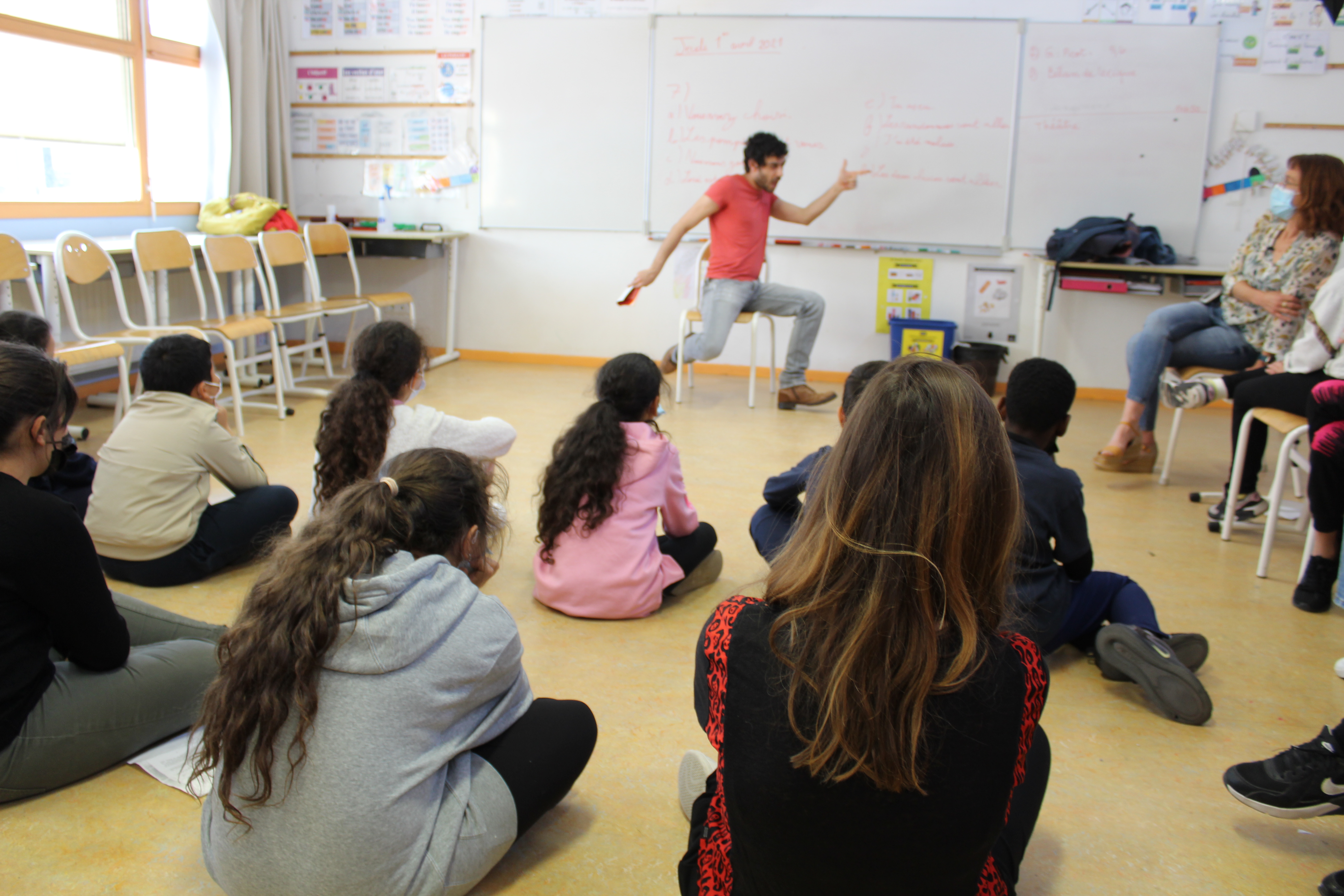 Antonio Carmona, auteur invité de cette 16e édition de THEA, est assis sur une chaise, face aux enfants, dans une position théâtralisée.