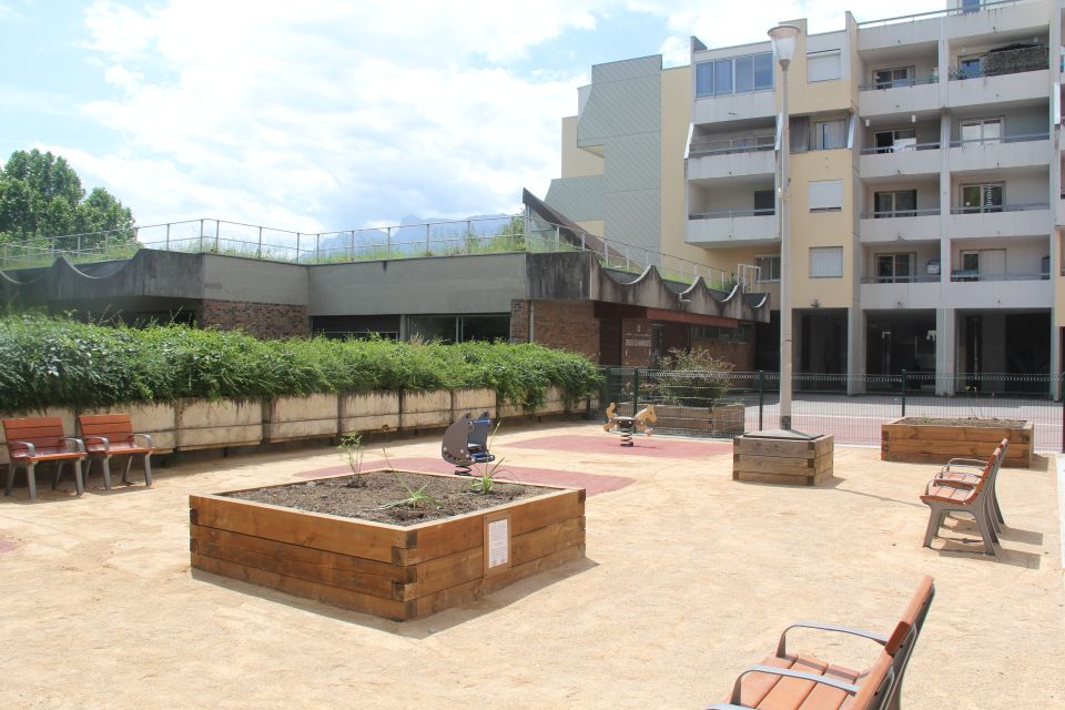 Photo du nouvel espace détente  place des Vosges. Nous voyons des bancs, des jeux pour enfants et des bacs pour des plantes.