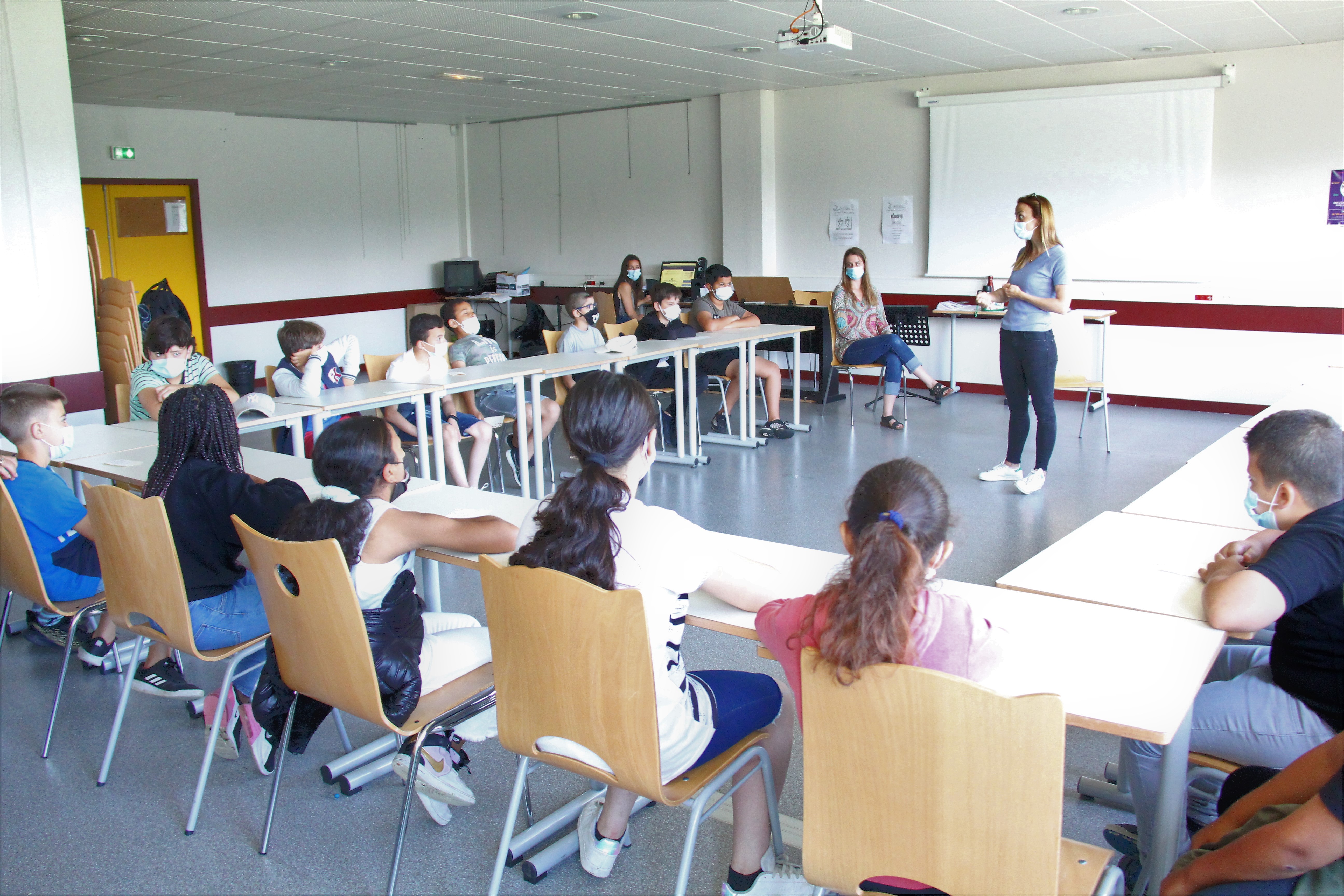 Photo prise dans le cadre du projet Projet philo-plastique. Nous voyons des élèves assis en "U" dans une salle de classe, avec leur enseignante. Comme lors des ateliers de Discussion à visée démocratique et philosophique, les élèves ont échangé sur leurs ressentis avec leur enseignante pour traduire leurs émotions.