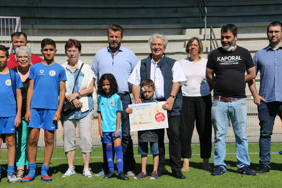 Photo prise à l'occasion de la remise des premiers Chèques sport avec les élus de la Ville, OSE et le FCE. Nous voyons le maire et les élu-es qui posent sur le terrain de foot avec les jeunes joueurs et les encadrants du club de foot.