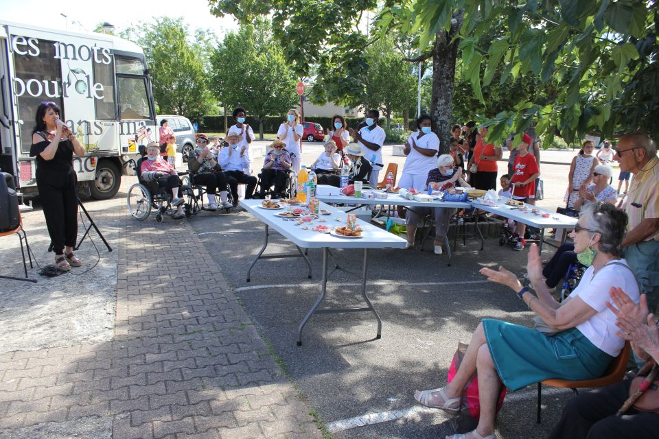 Bibliothèque éphémère : Une page se tourne... Photo de la chanteuse Maria Sulli qui donne un récital très apprécié par l'ensemble des participant-es confortablement installé-es à l'ombre du murier qui orne la place Melville.
