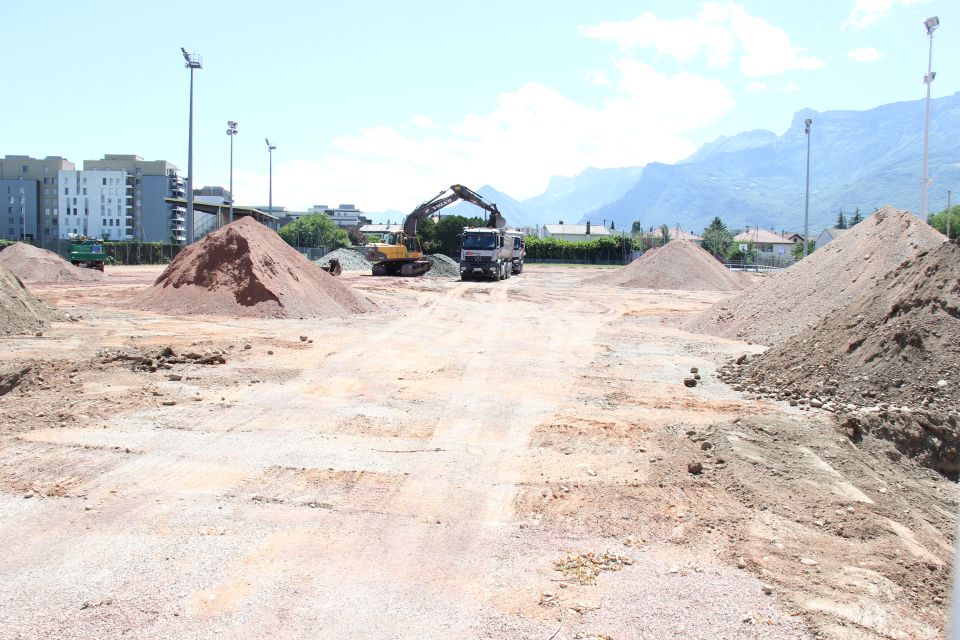 Photo des travaux du stade Delaune. Nous voyons des tas de sable et de gravier et des machines de chantier.