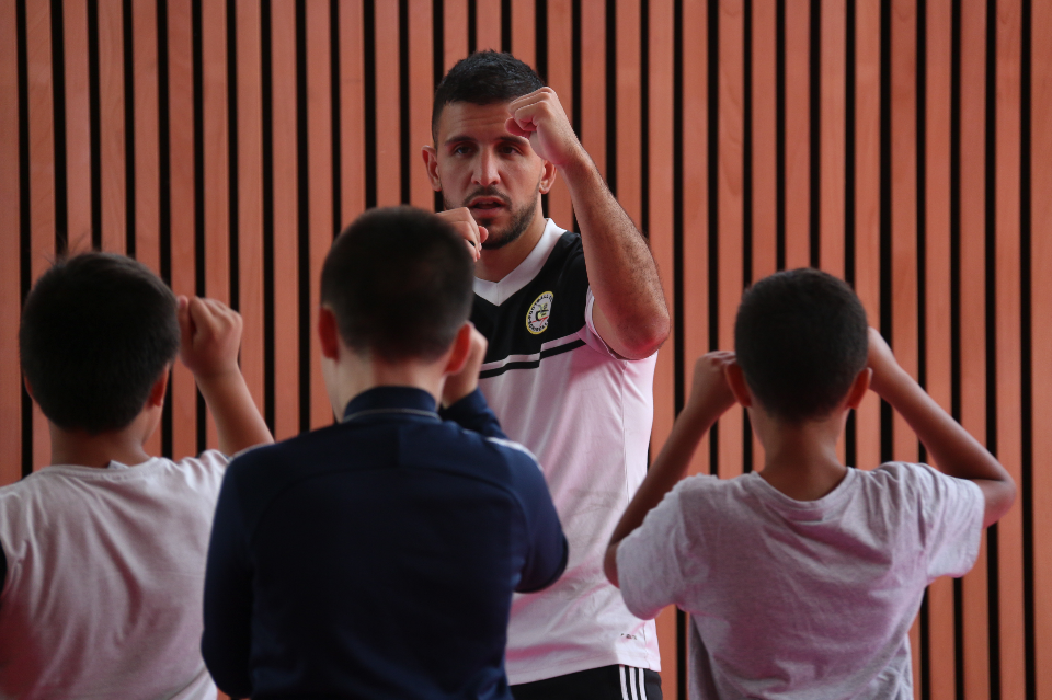 Eddy, éducateur sportif au club de boxe d'Échirolles et pour Atout sport Un éducateur sportif au club de boxe d'Échirolles apprend la bose à 3 jeunes garçons. Il leur montre le bon positionnement des bras pour se défendre et les jeunes l'imitent.