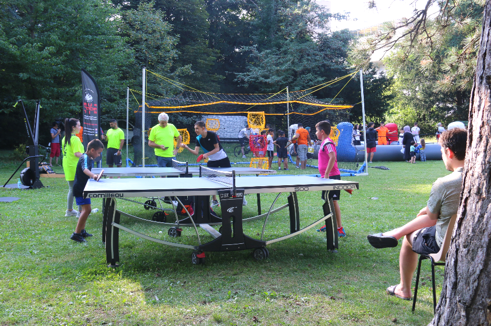 Ateliers sportifs. Des jeunes s'affrontent amicalement au ping pong au milieu du parc.