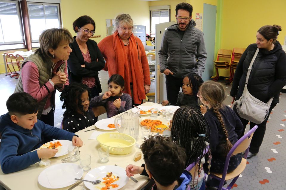 L'adjointe à l'éducation Jacqueline Madrennes, la première adjointe Amandine Demore, représentante de la Ville au conseil d'école, la directrice de territoire d'Evade, le responsable de la cuisine centrale et Carine, l'une des parents d'élèves (de gauche à droite), échangent avec les enfants avant le repas.