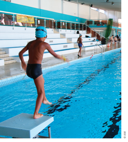 Enfant qui plonge dans la piscine intérieure du stade nautique