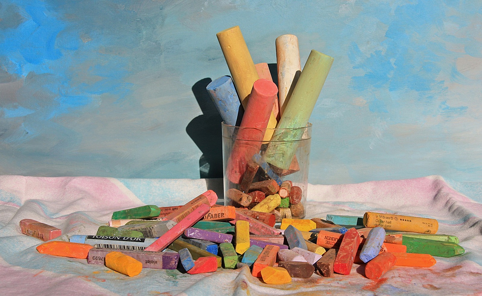 Pastel en Dauphiné Photo de craies. Certaines sont dans un verre, d'autres disposées autour du verre.