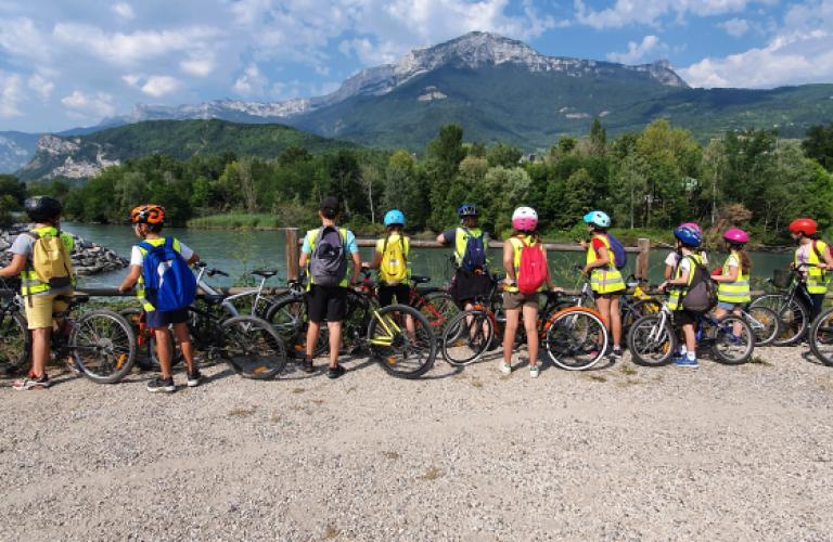 Photo d'un groupe de jeunes en sortie vélo avec Evade. Ils sont tous équipés de casques et gilets fluorescents.