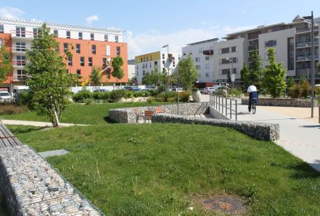 Le square es Cèdres, traversé par un cycliste, entouré de petits immeubles.