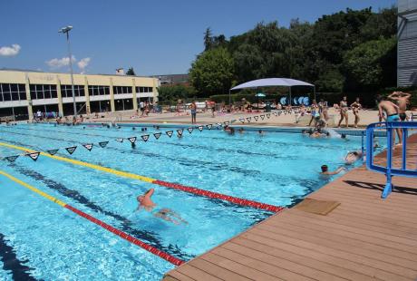 Dans le bassin de 50 m, certains nagent dans les lignes d'eau. Pendant ce temps, les ados se préparent à sauter dans l'eau. 