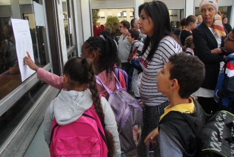 Parents et enfants examinent les listes affichées pour vérifier la composition des classes