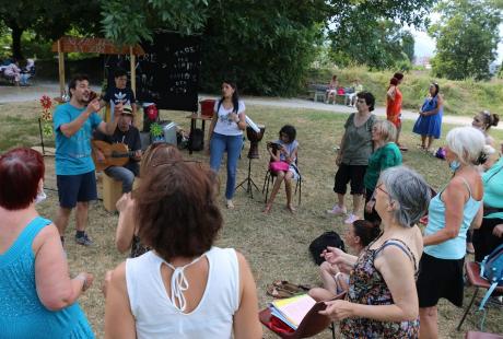 Les habitant-es participent à un atelier chant animé par Emmanuel Boudière au milieu du parc.