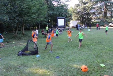 Match de foot entre des jeunes au milieu du parc. Chacun reconnaît son équipe grâce aux maillots vert et orange.
