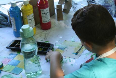 Atelier de création manuelle proposé par la Maison des habitant-es Village Sud. Ce jeune garçon s'applique à peindre.