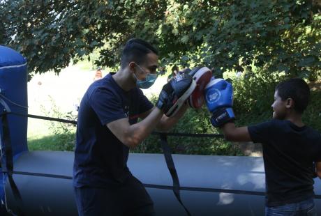 Expérimentation d'un combat de boxe entre un jeune et un animateur sur un ring gonflable.