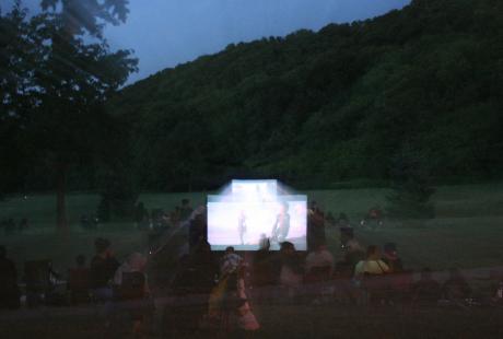 Cinéma en plein air. Le film est projeté sur une toile blanche installée au milieu du parc.