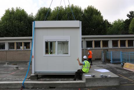 Les ouvriers positionnent le module correctement avant que celui-ci ne soit définitivement fixé sur les poteaux.