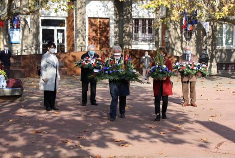 Le maire Renzo Sulli et l'adjointe au travail de mémoire Jacqueline Madrennes se dirigent vers le Monument aux morts, avec des gerbes de fleurs.