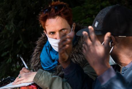 Photo de Marie Mazille et d'un habitant. Ils sont assis sur un banc et discute. Marie est à l'écoute de ce que l'habitant raconte pour créer une chanson  