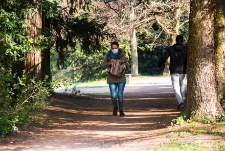 Marie Mazille marche sur une allée du parc en portant son accordéon. 