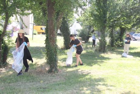  Photo prise dans le cadre de l'opération Ville propre.  Nous voyons des bénévoles, équipées de  gants, de pinces et de sacs, ramassant les déchets par terre.