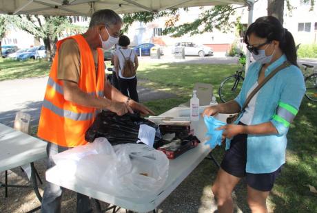 Photo prise à l'occasion de l'opération ville propre. Nous voyons des agents préparer les gants, sacs, brassards et pinces, tout le matériel mis  à disposition des participant-es sur le stand de la Luire, au pied des immeubles.