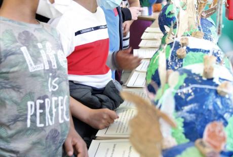 Photo prise dans le cadre du Projet Philo-plastique. Nous voyons des maquettes de la terre réalisées avec du plastique pour sensibiliser aux enjeux écologiques. Des jeunes regardent ces maquettes et discutent à leur sujet et au message qu'elles sont censées transmettre.