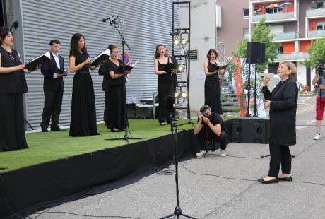  Photo de la présentation de saison la Rampe-La Ponatière pour la saison 2021-2022. Nous voyons Le chœur Spirito sur scène. Les chanteurs et chanteuses sont habillé-es en noir et blanc. Ils intérprètent un de leur morceau sous la direction de leur cheffe de choeur, Nicole Corti.