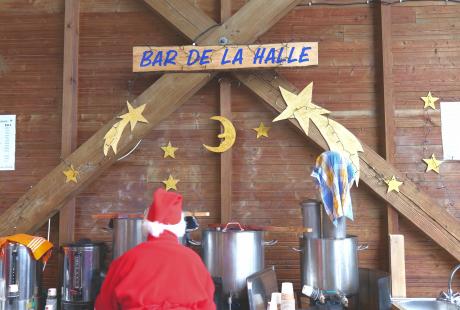 Photo du bar de la Halle, avec un bénévole qui s'affaire devant la marmite de vin chaud arrière-plan