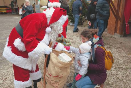 Le Père Noel distribuant une papillotte à une petite fille au Marché de Noël