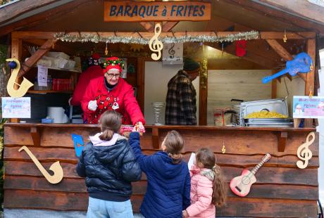 Photo de la baraque à frites du marché et d'une bénévole donnant des papillottes aux enfants