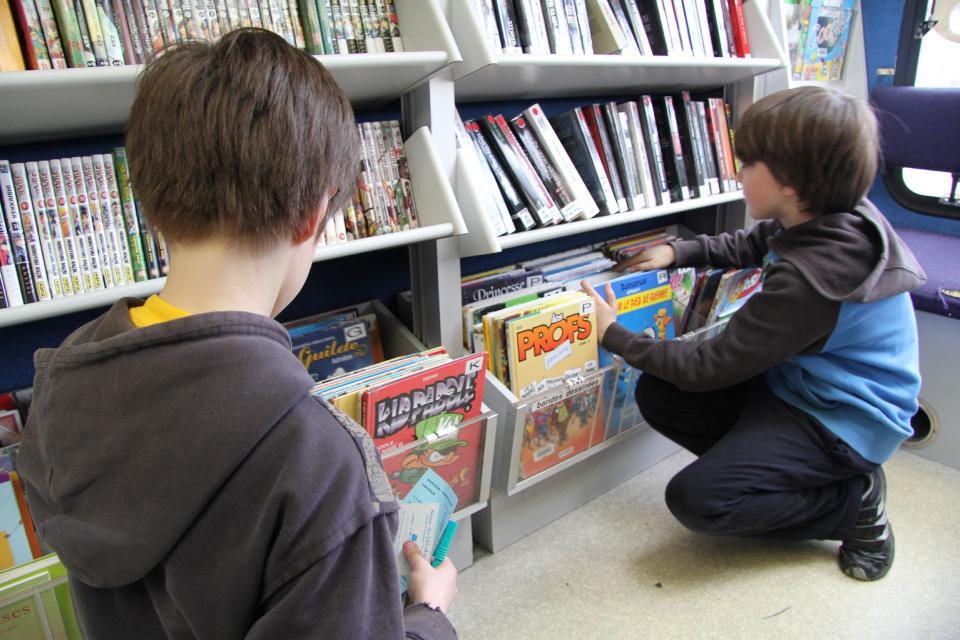 Bibliothèque Des enfants regardent des livres sur les rayons du bouquinbus