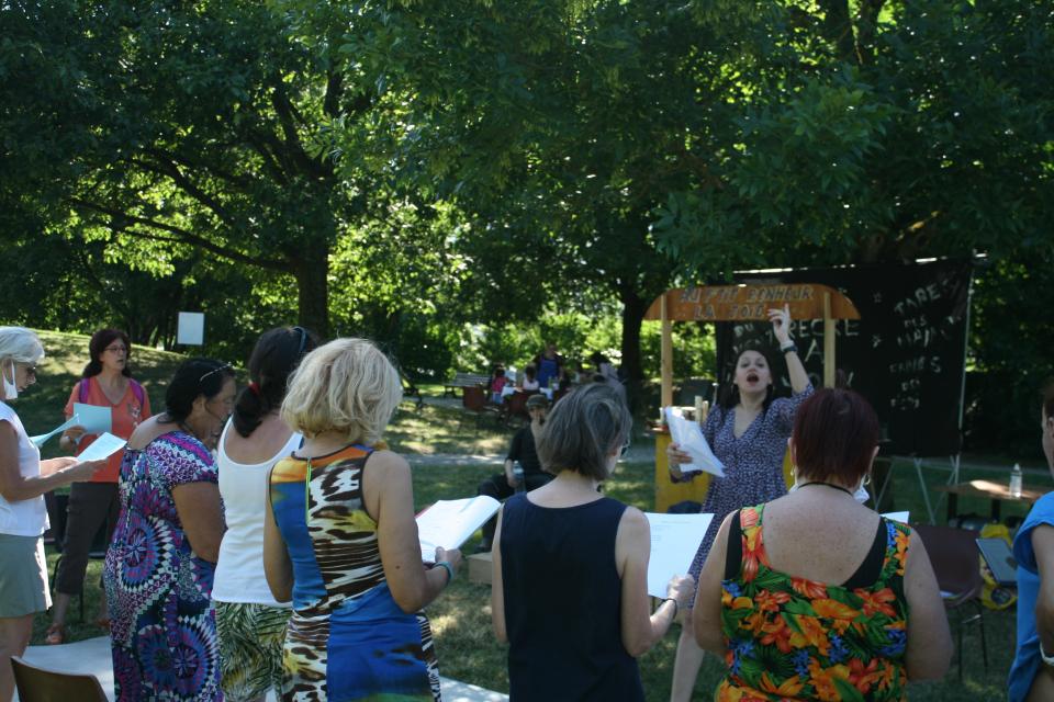 Répétition en plein air pour cette chorale. La chef de chœur rythme les départs des chants.