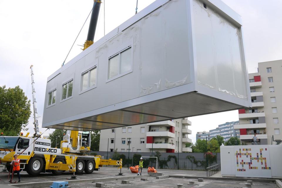 Travaux école Jean-Paul-Marat, 6 modules ont été déposés Un module est soulevé, déplacé et positionné dans la cours de l'école par une grue.